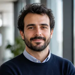 Professional author portrait with neutral background, smart casual attire, suitable for editorial website author block.